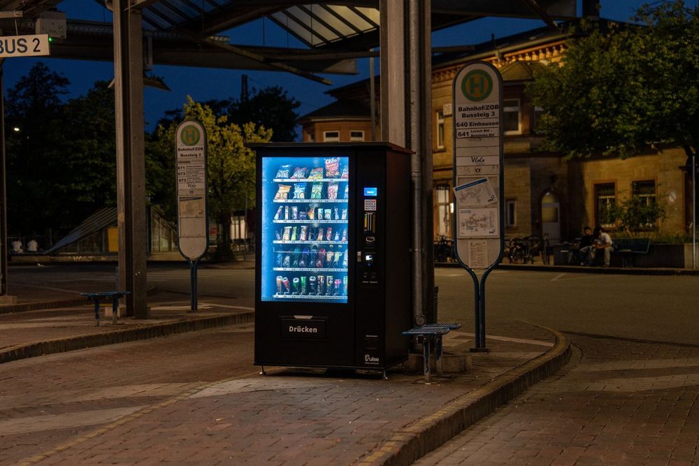 Beleuchteter Pulse PV1100 Snackautomat verkauft abends am menschenleeren Busbahnhof