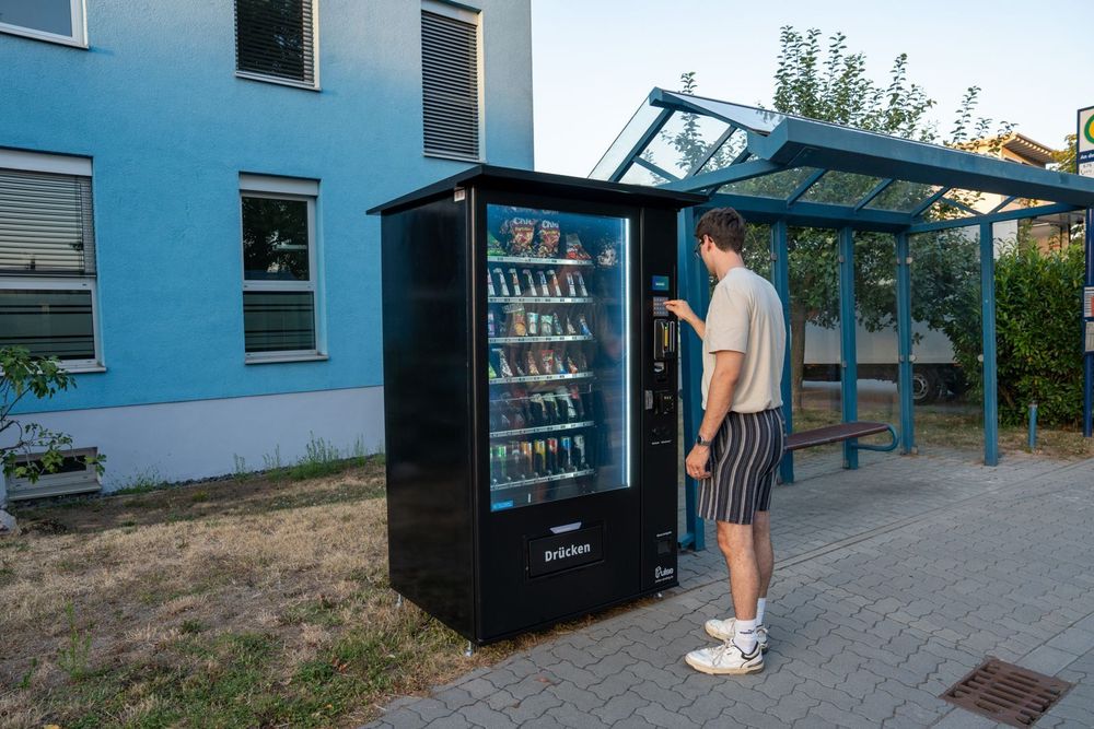Kunde wählt ein Produkt am Pulse PV1100 Snackautomaten an einer Bushaltestelle