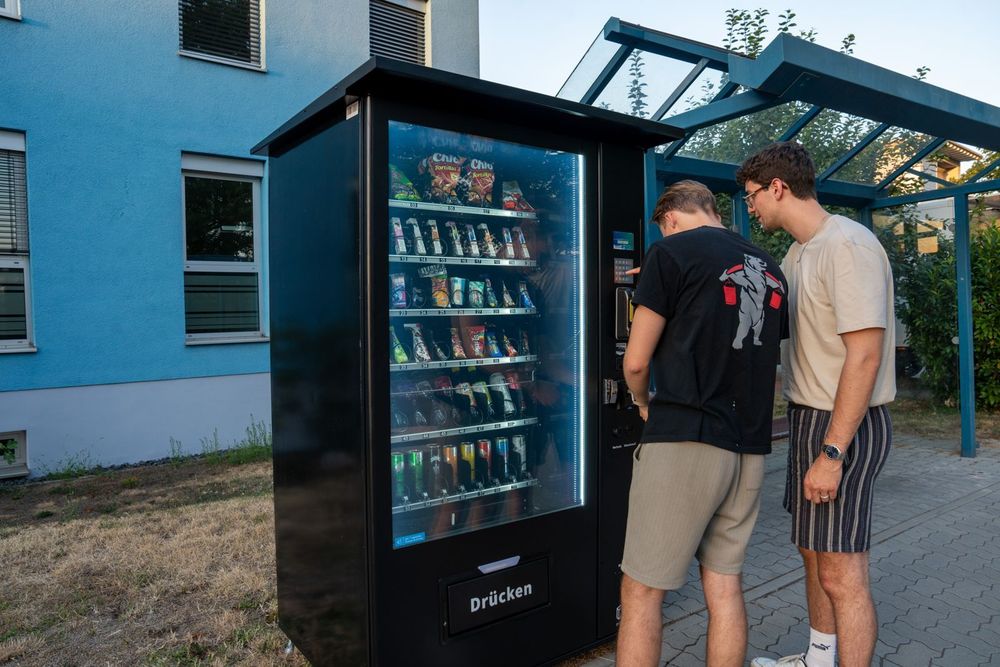 Zwei Kunden kaufen am Pulse PV1100 Snackautomaten an einer Haltestelle ein